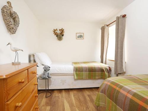 a bedroom with two beds and a dresser and a window at Kielder Cottage - E3533 in Kielder