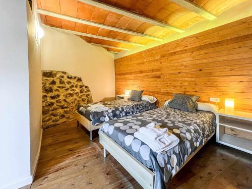 Duas camas num quarto com paredes de madeira em CAN FRUITÓS Alojamiento rural en Besalú em Besalú