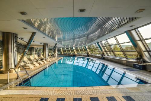 a large swimming pool in a building with windows at Hotel Belweder in Ustroń
