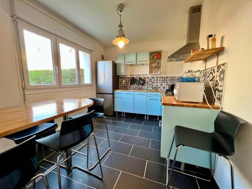 une cuisine avec des armoires bleues et des chaises noires dans l'établissement COC - La Rafale, à Wissant