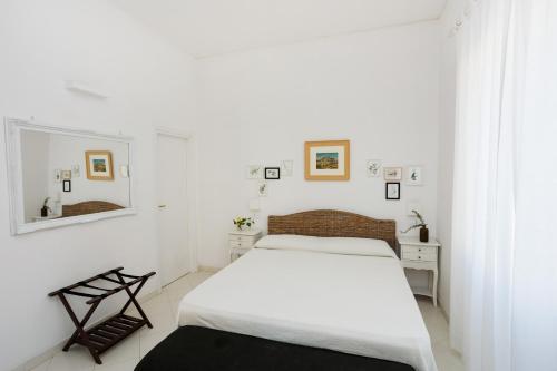 - une chambre blanche avec un lit et un miroir dans l'établissement Villa l'Approdo, à Anacapri
