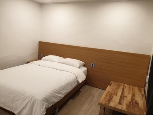 a bedroom with a bed with a wooden headboard and a table at Seorak HOT Spring Mammoth Resotel in Sokcho