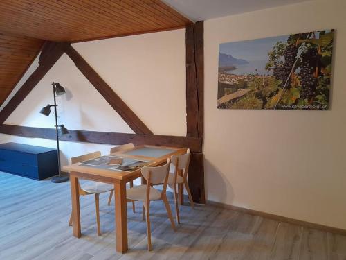 een eetkamer met een houten tafel en stoelen bij Studio mansardé chez un vigneron au village in Villeneuve