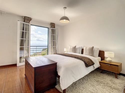 una camera da letto con un letto grande e una grande finestra di Villa Formosa View by Atlantic Holiday a Funchal