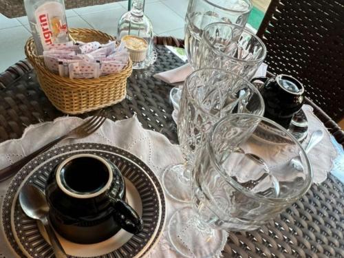 a table topped with glasses and a plate with a tea pot at Pousada da Leide in Fernando de Noronha