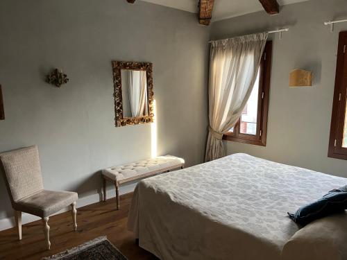 a bedroom with a bed and a chair and a mirror at Palazzo Veneziano direct at the canal with roof terrace in Venice