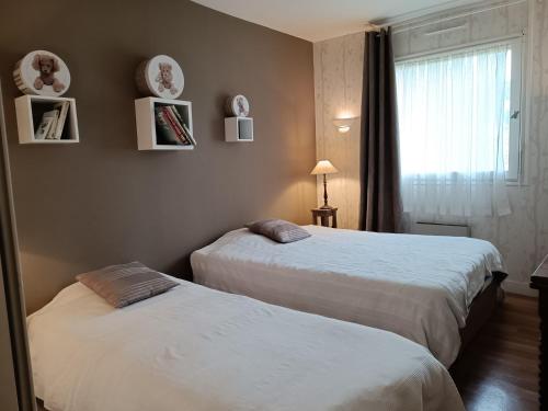 deux lits dans une chambre d'hôtel avec une fenêtre dans l'établissement Appartement Trouville-sur-Mer vue mer imprenable, à Trouville-sur-Mer