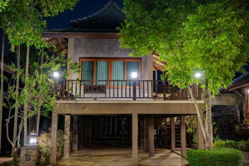 a house with a balcony at night at มนต์เมืองเชียงใหม่ รีสอร์ต Monmuang Chiangmai Resort in Hang Dong