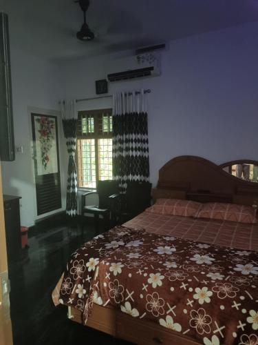 a bedroom with a bed with a brown blanket with flowers at Oxygen Home Stay in Agali