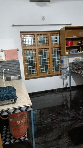 a kitchen with a table and a counter with windows at Oxygen Home Stay in Agali