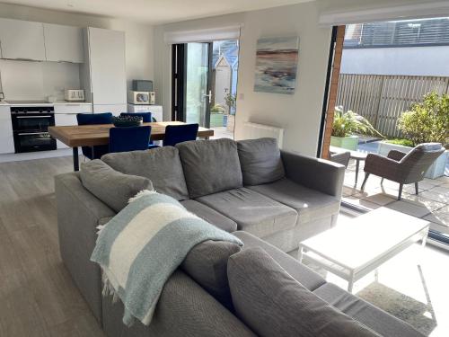 Una sala de estar con un sofá gris y una mesa. en 3 Middlecombe - Luxury Apartment at Byron Woolacombe, only 4 minute walk to Woolacombe Beach!, en Woolacombe