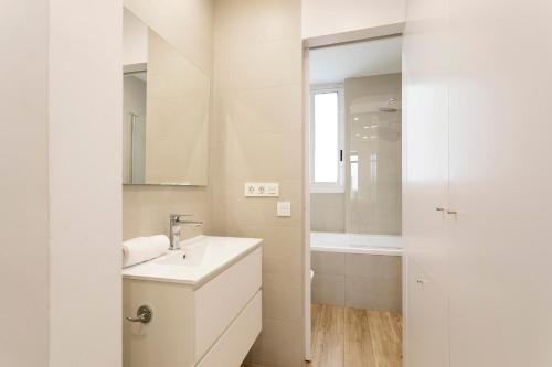La salle de bains blanche est pourvue d'un lavabo et d'une baignoire. dans l'établissement AB Passeig de Gràcia Casa Batlló, à Barcelone