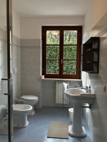 a bathroom with two sinks and a toilet and a window at Acero in Cortona