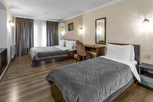 Habitación de hotel con 2 camas y escritorio en Moss Art Boutique Hotel en Bakú