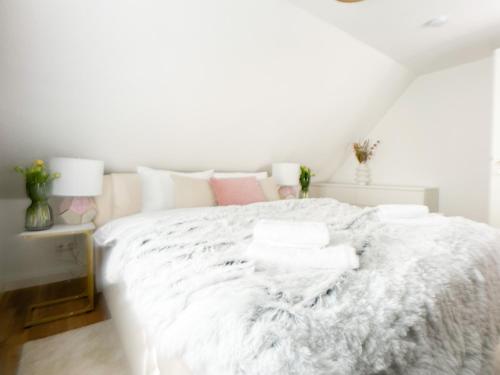 een wit bed met witte lakens en roze kussens bij M-Style 03 Apartment 24h Self-Check-In, Free Parking, Netflix in Neurenberg