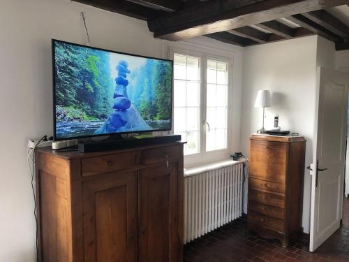 TV de pantalla plana en un soporte de madera en una habitación en Les Volets Bleus-Charmante maison entièrement équipée face à la mer pour 2 à 6 personnes en Bernières-sur-Mer