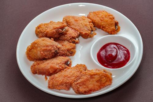 a plate with fried food and a bowl of ketchup at มนต์เมืองเชียงใหม่ รีสอร์ต Monmuang Chiangmai Resort in Hang Dong