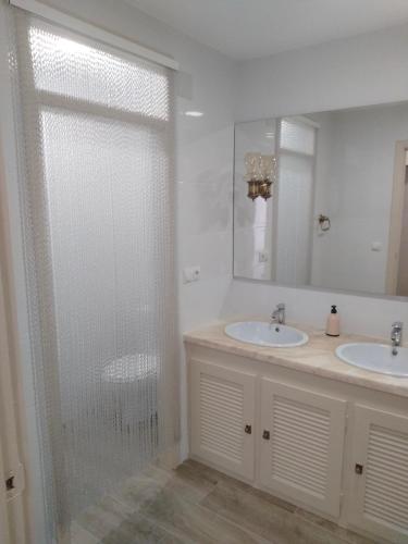 a bathroom with two sinks and a shower with a glass door at City Centre apartments in Denia