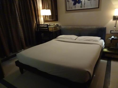 a bedroom with a large bed with white sheets at HOTEL SAPNA MARINE in Mumbai