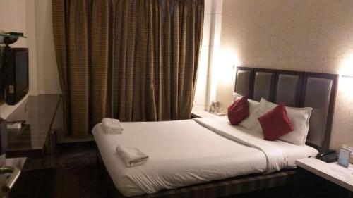 a bedroom with a large white bed with red pillows at HOTEL SAPNA MARINE in Mumbai