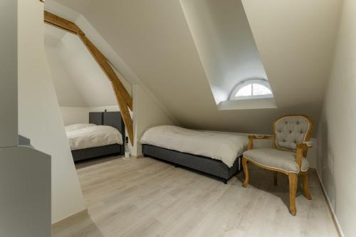 een slaapkamer op zolder met 2 bedden en een stoel bij De zandberg Vakantiewoning in Neerpelt