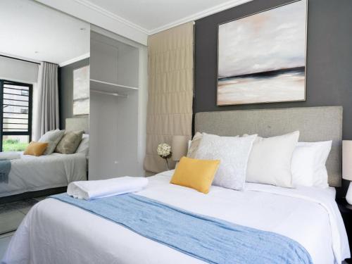 a bedroom with a large white bed with a yellow pillow at Royal on 81 Ventura in Fourways