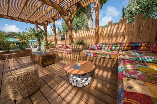 a patio with couches and a table and a fence at Camping Antioche D'Oléron in La Brée-les-Bains