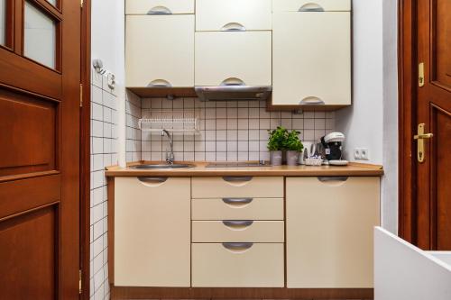a kitchen with white cabinets and a sink at HappyStay Grandma Apartment in Gdańsk