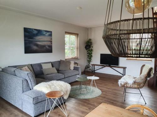 a living room with a gray couch and chairs at Buitenplaats Villa Deluxe in Callantsoog
