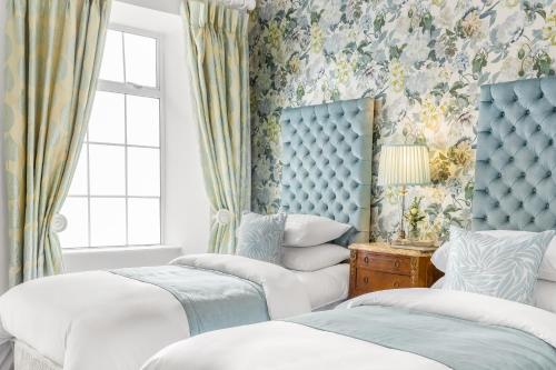 um quarto com 2 camas e papel de parede floral em An Sugan Guesthouse em Clonakilty