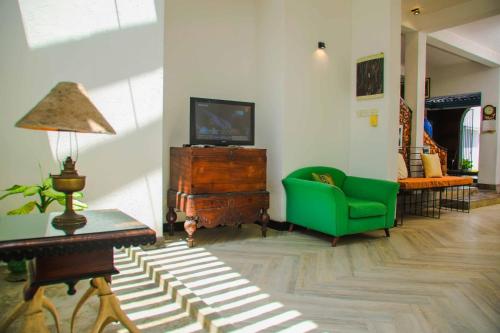 a living room with a green couch and a tv at Tranquill Villa La Dimora in Gampaha