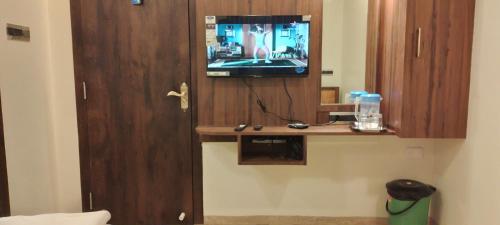 a room with a tv and a wooden cabinet at Shine Hospitality Palace in Mumbai