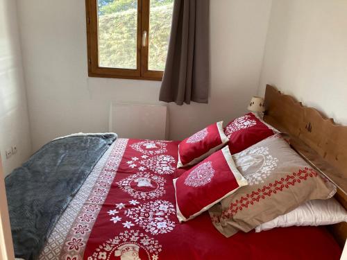 uma cama com cobertores e almofadas vermelhos e brancos em Appartement LA MARMOTTE DU DEVOLUY em Le Dévoluy