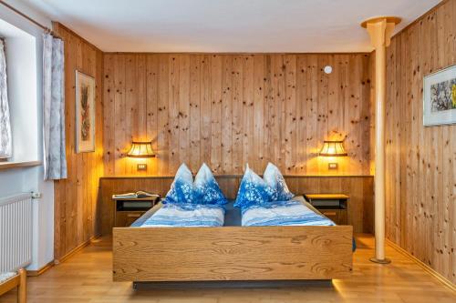 Un dormitorio con una cama con almohadas azules. en Stöcklhuberhof, en Vandoies