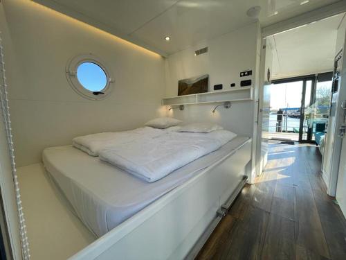 een groot wit bed in een kamer met een raam bij Houseboat Kamperland in Kamperland