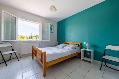 une chambre avec un lit et un mur bleu dans l'établissement Gîte L'Orée du Lac, à Carcassonne
