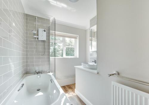 a white bathroom with a tub and a sink at 1 Lux Farm Cottages in Playford