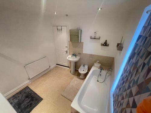 a bathroom with a tub and a toilet and a sink at Impeccable 3-Bed Home Away From Home in Swindon in Swindon