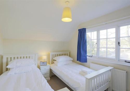 two beds in a white room with a window at 10 The Whinlands in Thorpeness