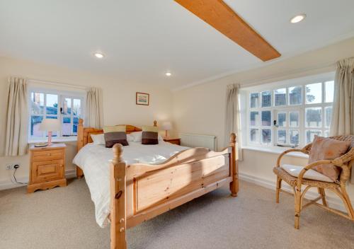 a bedroom with a bed and a chair and windows at 1 The Knoll in Shottisham