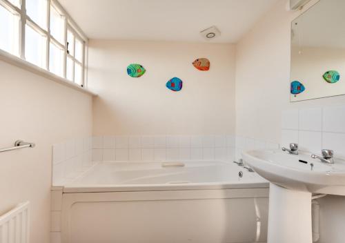ein weißes Badezimmer mit einer Badewanne und einem Waschbecken in der Unterkunft 1 The Knoll in Shottisham