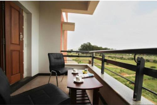 a room with a balcony with a table and a chair at ZIONS HOTEL AND APERTMENT in Devanahalli-Bangalore