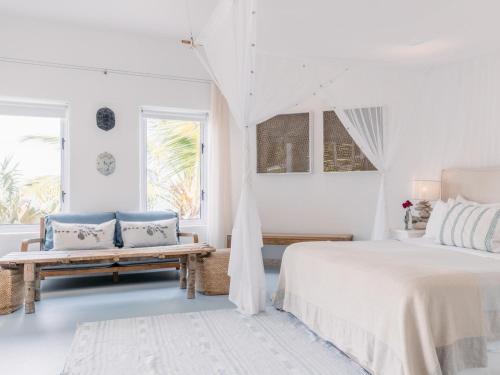 a white bedroom with a bed and a bench at Villa Santorini in Vilanculos