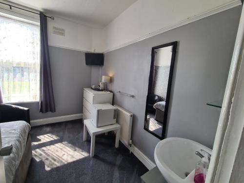 een badkamer met een wastafel en een spiegel bij The Roslyn Guest House in Paignton