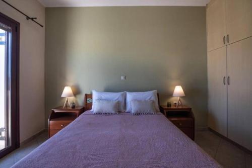 sypialnia z dużym łóżkiem z fioletową pościelą i 2 lampami w obiekcie Terpsis House w mieście Kisamos