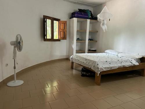 1 dormitorio con 1 cama y ventilador. en Complete House in the jungle, near the sea., en Kafountine