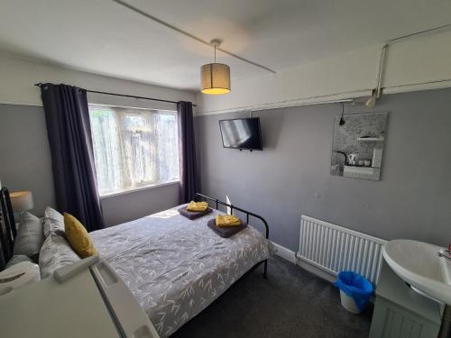 een slaapkamer met een bed, een wastafel en een raam bij The Roslyn Guest House in Paignton