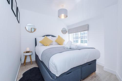 a white bedroom with a large bed with yellow pillows at Stylish Home with Canal Views in Chester