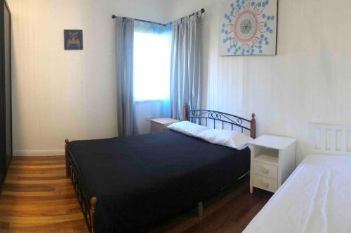 1 dormitorio con cama negra y ventana en Queenslander in the heart of Atherton - Spotless en Atherton