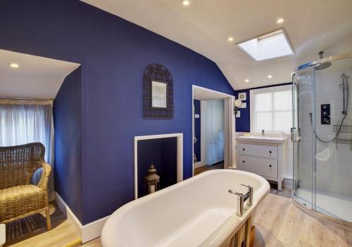 ein Badezimmer mit einer weißen Badewanne und einer blauen Wand in der Unterkunft 4 Doric Place in Woodbridge